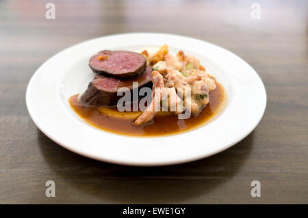 Sella alla griglia di cervi, polpo alla griglia, vestirsi di arancione e rosa lo zenzero, carne di cervo demi-glace, profondità di campo Foto Stock