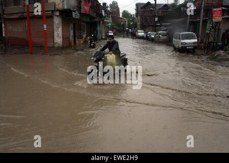 Srinagar, Indiano Kashmir amministrato. Il 24 giugno 2015. Un motociclista sposta lungo una strada sotto la pioggia durante la Heavy Rain flagellato ampie parti della valle del Kashmir, compresi capitale estiva di Srinagar, influenzando negativamente il traffico e le attività di business qui.docce per continuare fino a giugno 28 Credito: Sofi Suhail/Alamy Live News Foto Stock