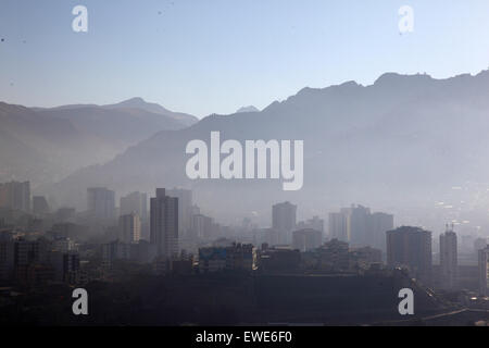 La Paz, Bolivia, 24 giugno 2015. Il fumo riempie le valli del centro di la Paz poco dopo l'alba dopo la notte di San Juan. San Juan è tradizionalmente ritenuta la parte più fredda dell'anno e molte persone in Bolivia accendono falò e scatenano fuochi d'artificio. Negli ultimi anni le autorità locali hanno tentato di fermare questa usanza per ridurre l'inquinamento in eccesso che causa in città, ma con un successo limitato. Questa vista si affaccia ad est da Sopocachi al quartiere di Miraflores e ai piedi delle Ande. Foto Stock