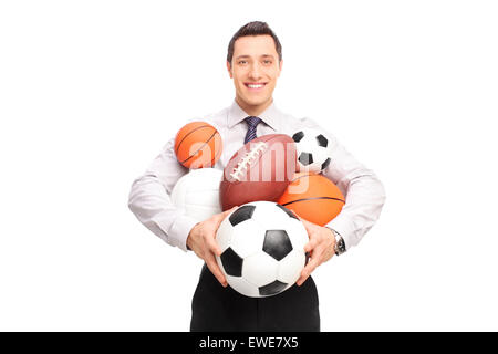Giovane uomo tenendo un mazzetto di diverso tipo di palloni e guardando la telecamera isolata su sfondo bianco Foto Stock