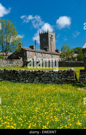 St Oswalds Chiesa, Askrigg in Wensleydale, visto su un prato di fiori selvaggi all'inizio dell'estate. Yorkshire, Regno Unito. Foto Stock