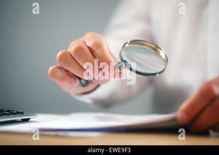 Imprenditore con lente di ingrandimento lettura di documenti Foto Stock