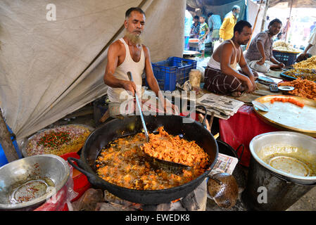 Un uomo che fa cibo per vendita a Kaikkarateke mercato settimanale, Narayanganj distretto in Bangladesh, il 21 giugno 2015 Foto Stock