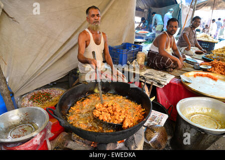 Un uomo che fa cibo per vendita a Kaikkarateke mercato settimanale, Narayanganj distretto in Bangladesh, il 21 giugno 2015 Foto Stock