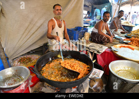 Un uomo che fa cibo per vendita a Kaikkarateke mercato settimanale, Narayanganj distretto in Bangladesh, il 21 giugno 2015 Foto Stock