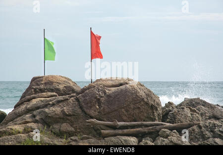 Verde e bandiera rossa su una roccia da una spiaggia in Sri Lanka, in Asia. Foto Stock