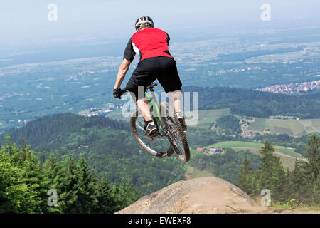 Vista posteriore della mountain bike rider che salta su una pista sterrata kicker. Foto Stock