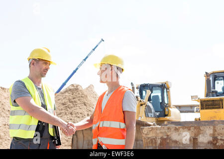Gli architetti si stringono la mano al sito in costruzione contro il cielo chiaro Foto Stock