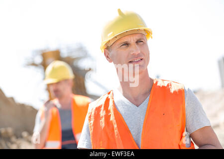 Lavoratore di sesso maschile in cantiere con il collega in piedi in background Foto Stock