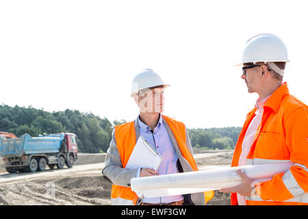 Ingegneri discute al sito in costruzione contro il cielo chiaro Foto Stock