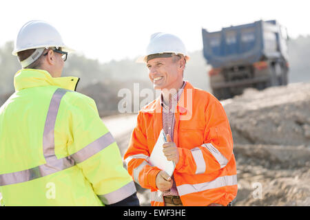 Ingegnere felice discutendo con un collega sul sito in costruzione sulla giornata di sole Foto Stock