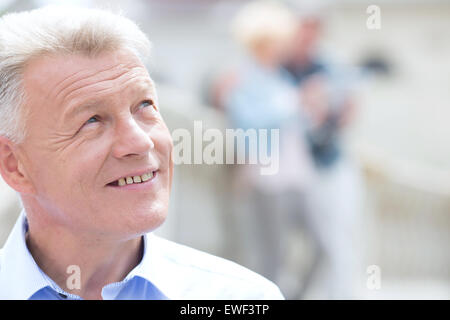 Close-up di uomo sorridente che guarda lontano all'aperto Foto Stock