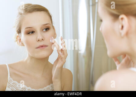 Giovane donna l'applicazione di crema di bellezza, vicino fino Foto Stock