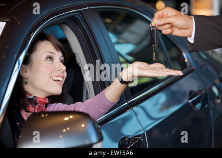 Giovane donna riceve le chiavi della macchina dal venditore auto Foto Stock