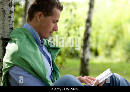 Giovane uomo libro lettura in posizione di parcheggio Foto Stock