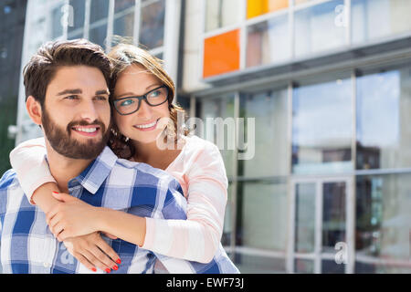 Amare l uomo donna piggybacking in città Foto Stock