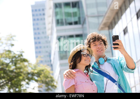 Coppia sorridente tenendo ritratto di auto al di fuori di edificio per uffici Foto Stock