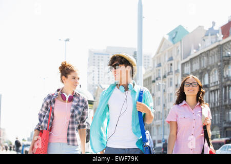 Happy amici parlando mentre passeggiate in città Foto Stock