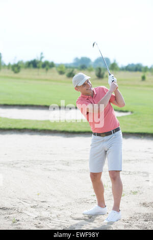 Uomo di mezza età swinging al campo da golf Foto Stock