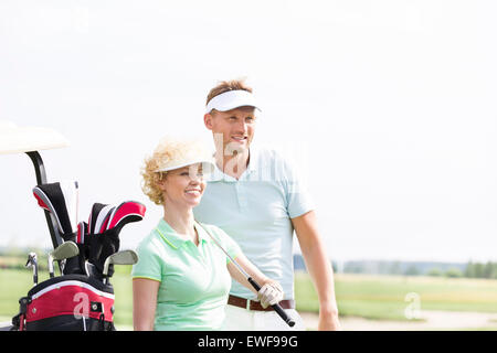 Sorridente golfisti permanente al campo da golf contro il cielo chiaro Foto Stock