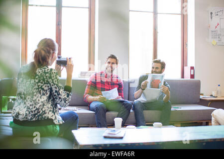 Imprenditore creativo in posa con la fotografia di un collega con instant telecamera in ufficio Foto Stock