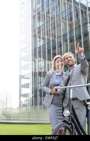 Happy businessman mostrando qualcosa di imprenditrice in città Foto Stock