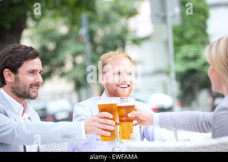 Happy businessman tostare bicchieri da birra presso un ristorante esterno Foto Stock