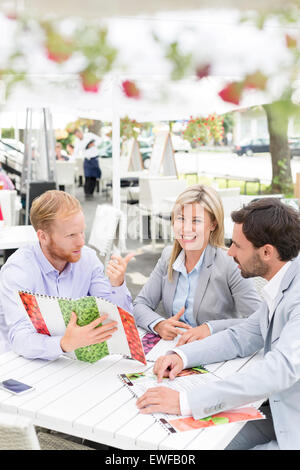 Ritratto di felice imprenditrice con colleghi di sesso maschile di decidere menu al cafè sul marciapiede