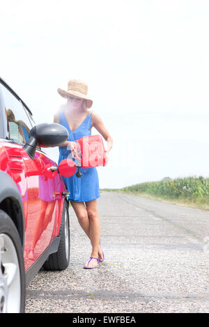 Per tutta la lunghezza della giovane donna il rifornimento auto sulla strada di campagna Foto Stock