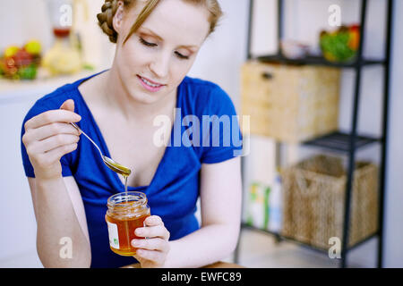 Donna di mangiare il miele Foto Stock