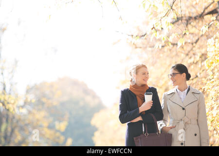 Felice imprenditrici a conversare mentre passeggiate al parco sulla giornata di sole Foto Stock