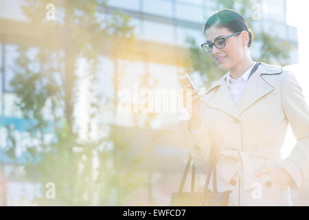 Imprenditrice utilizzando smart phone sulla giornata di sole Foto Stock
