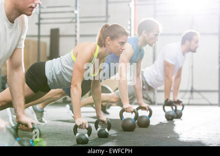 Determinate persone facendo pushups con kettlebells crossfit in palestra Foto Stock