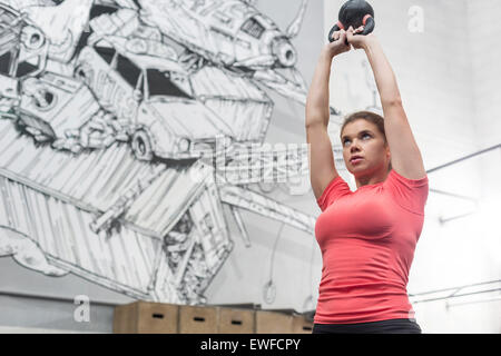 Basso angolo di visione della donna dedicato il sollevamento kettlebell in palestra crossfit Foto Stock
