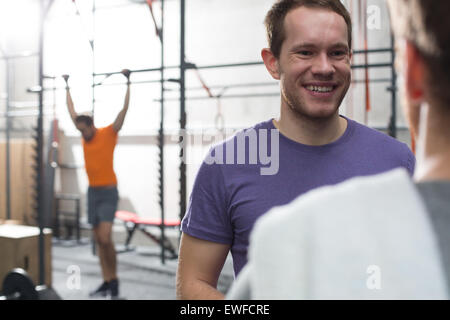 Uomo felice di parlare a maschio amico in palestra crossfit Foto Stock