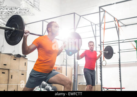 Gli uomini il sollevamento barbells in palestra crossfit Foto Stock