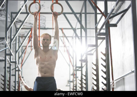 Fiducioso uomo esercitando con anelli di ginnastica in palestra crossfit Foto Stock