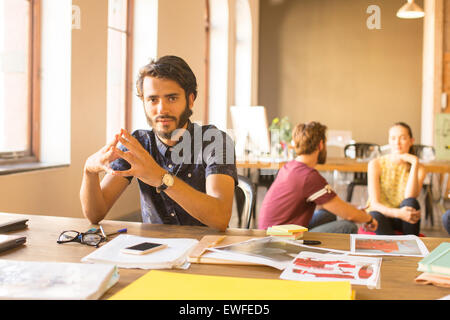 Ritratto fiducioso imprenditore creativo lavorare con prove di stampa in ufficio Foto Stock