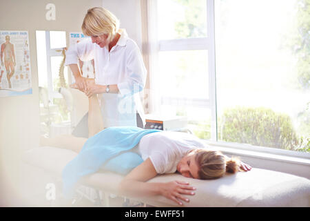 Fisioterapista massaggiare i piedi femminili Foto Stock