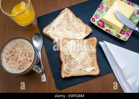 Una speciale colazione con succo d'arancia, caffè e due toast con burro Foto Stock