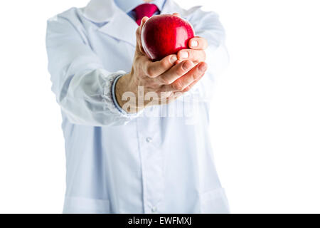 Maschio caucasico medico vestito in camice bianco, blu camicia e cravatta rossa è che mostra una mela rossa Foto Stock