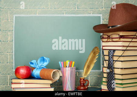 Jesting insolita insegnante, libri, quill, penna, scorrere Apple prima di lavagna con spazio di copia Foto Stock