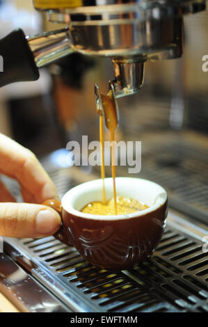 Caffè alimentari Cafe Espresso bevande servite in una demitasse tazza di ceramica con un barista tenendo la coppa Foto Stock