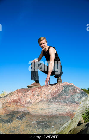 Bionda uomo agisce raffreddare su big rock Foto Stock