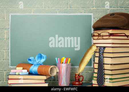 Jesting insolita insegnante, libri, quill, penna, scroll chalk prima di lavagna con spazio di copia Foto Stock