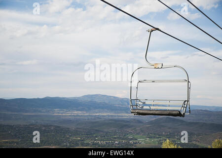 Un paesaggio invernale caratterizzato da un unico impianto di risalita vuoto sullo sfondo di una montagna innevata. Lo skilift viene utilizzato in genere per trasportare sciatori e snowboarder sulle piste. Foto Stock