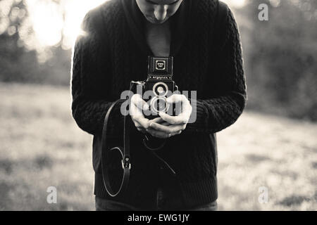 Una persona sta tenendo in mano la fotocamera Argus Argoflex e d'epoca, probabilmente sta scattando un autoritratto. La fotocamera è nota per il suo design a doppio obiettivo, che offre una prospettiva unica alla fotografia. Foto Stock