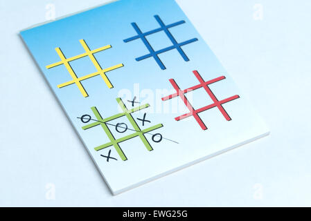 Una chiusura di un gioco di Xs e OS su un blocco note con colorati griglie fatte per la riproduzione. Foto Stock
