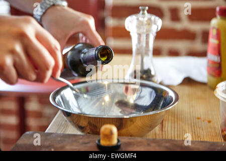 Lo chef prepara un condimento per insalata olio di oliva pepe ciotola argento vinaigrette a base di salsa di culinaria Foto Stock