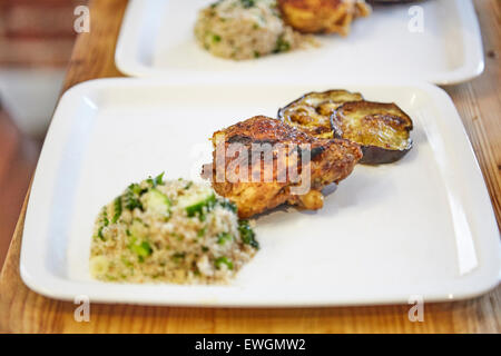 Il cous cous pollo alla griglia melanzane alla griglia su una piastra bianca Foto Stock